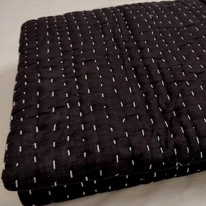 Queen Size black cotton quilt with fine white stitches.