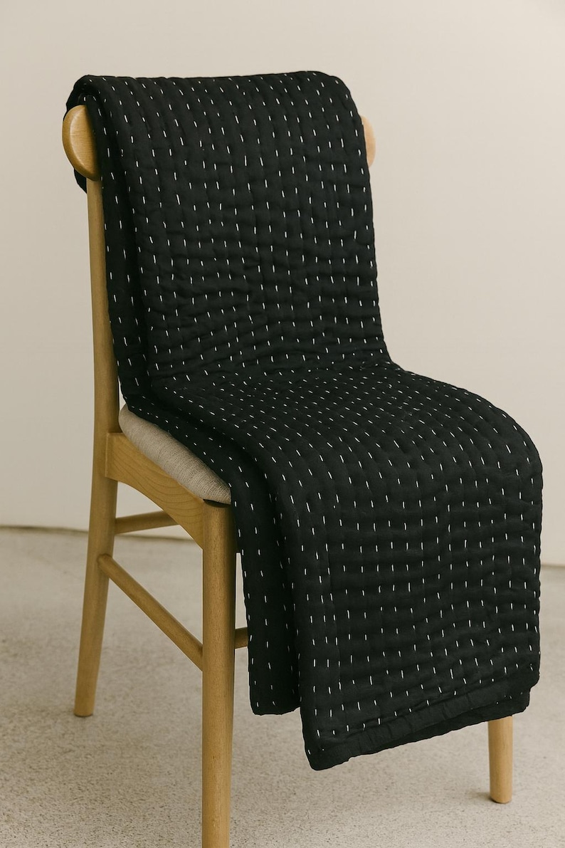 Handmade black Kantha quilt with white hand stitching.