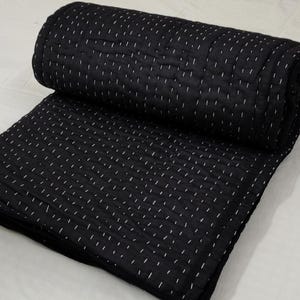 Folded black quilt featuring traditional hand quilting.