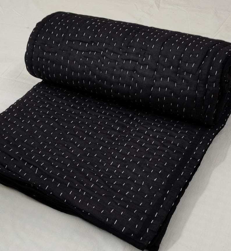 Folded black quilt featuring traditional hand quilting.