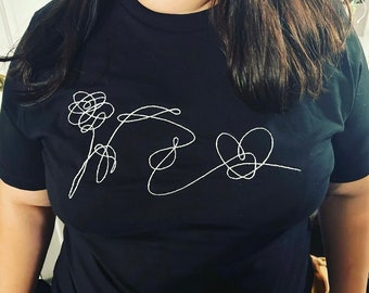 May include: Black t-shirt with a white embroidered design of a flower, a heart, and a stylized symbol.