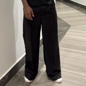 May include: A pair of wide-leg black pants with a straight leg and a slightly cropped length. The pants are made of a smooth, lightweight fabric and have a relaxed fit.