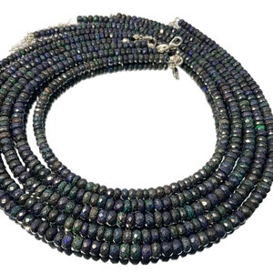 May include: Several strands of faceted black opal beads with iridescent colour flashes. The beads are strung with silver clasps, creating a layered necklace effect. The gemstones are displayed on a reflective surface.