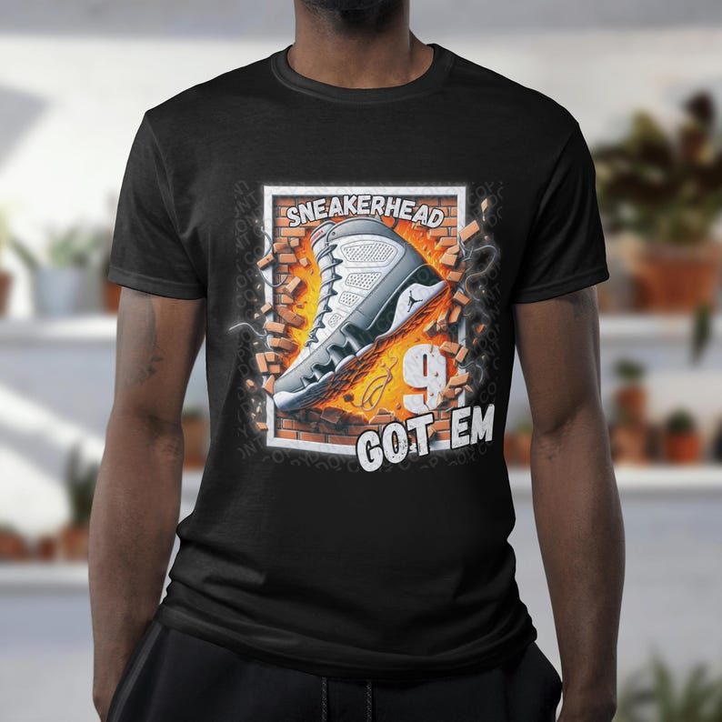 May include: Black t-shirt with a graphic of a white and grey sneaker breaking through a brick wall. The text "Sneakerhead 9 Got Em" is printed below the sneaker.
