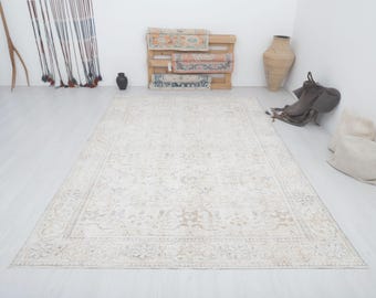 May include: A cream-colored rug with a floral pattern. The rug has a light brown border and is made of a soft, woven material.