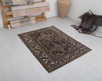 Puede incluir: Una alfombra de color marrón y azul con fondo beige. La alfombra tiene un diseño geométrico con un medallón central.