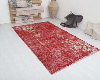 Könnte beinhalten: Ein roter Vintage-Teppich mit einem verblassten Blumenmuster. Der Teppich hat einen abgenutzten Look und ist aus einem weichen, strapazierfähigen Material gefertigt.