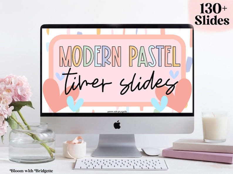 Pu&ograve; includere: Uno schermo di computer che mostra uno sfondo rosa con il testo "MODERN PASTEL timer slides" in lettere colorate. Lo schermo &egrave; circondato da una cornice argentata e si trova su una scrivania bianca con una tastiera, un vaso di fiori e una candela.