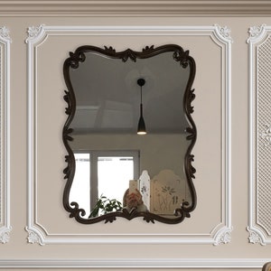 Puede incluir: Dos sillones de color amarillo mostaza con almohadas, una mesa de centro de metal dorado con tapa de cristal y una lámpara de pie dorada con pantalla blanca en una habitación con molduras blancas ornamentadas y un gran espejo ornamentado.