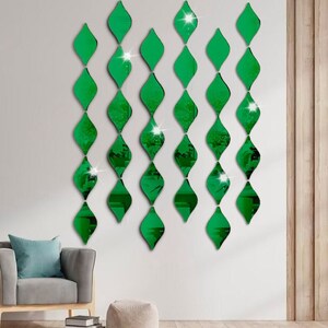 May include: A set of 18 green diamond-shaped wall mirrors arranged in a vertical pattern on a white wall. The mirrors are reflective and create a shimmering effect.
