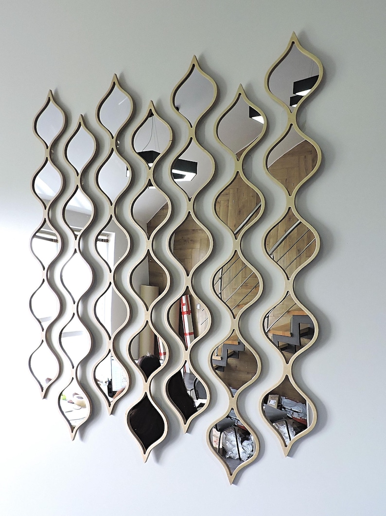 May include: A set of decorative wall mirrors with a unique, flowing design. Each mirror is framed in a light wood color and features an elongated, teardrop shape. The mirrors are arranged in vertical, wavy patterns, creating a modern aesthetic.