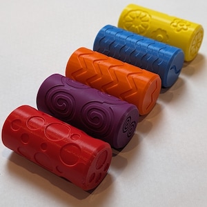 May include: Five colourful rolling pins with different patterns. The rolling pins are red, purple, orange, blue and yellow.
