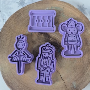 May include: Set of four purple plastic cookie cutters featuring a ballerina, a nutcracker, a mouse king, and a balcony.