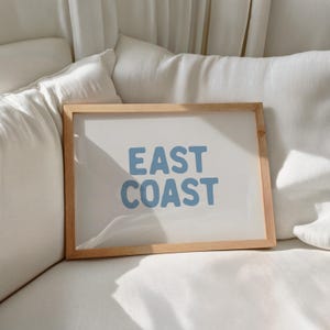 Minimalist typography wall art featuring the words “East Coast” in soft blue lettering on a clean off-white background. A modern, coastal-inspired print perfect for beach house decor, summer homes, living rooms, bedrooms or relaxed contemporary spaces. The simple design and airy colour palette create an effortless, laid-back seaside feel. This listing is for a digital download only. No physical print or frame included.