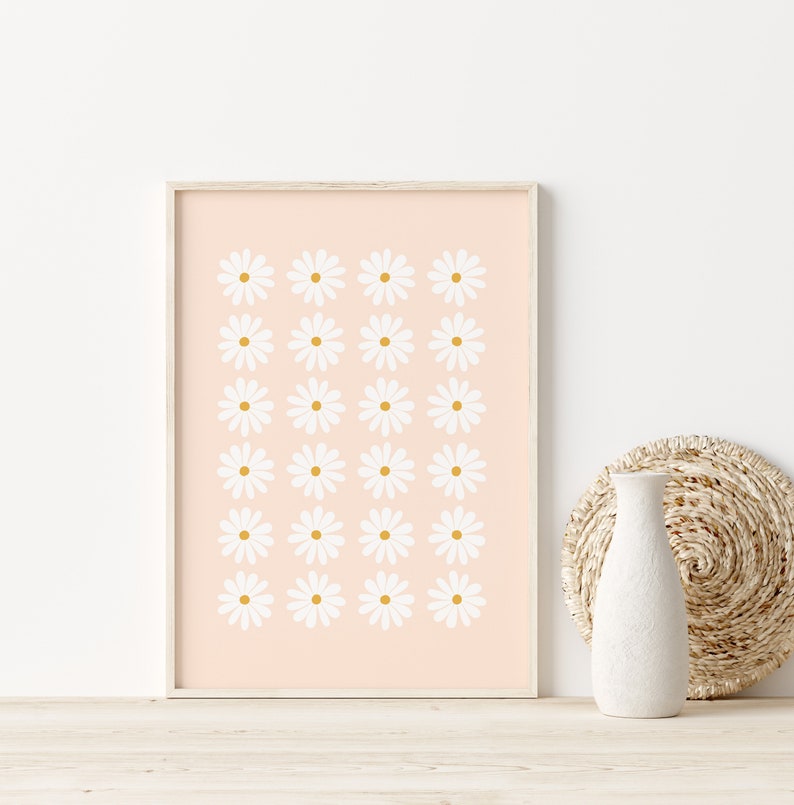 May include: A framed print with a pattern of white daisies on a light pink background.