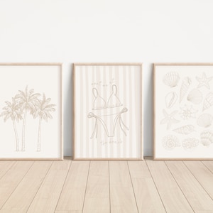 May include: Three framed prints with a beach theme. The left print features a line drawing of three palm trees. The centre print has a striped background with a line drawing of a bikini and the text "Meet me at the beach". The right print features a line drawing of various seashells and a starfish.