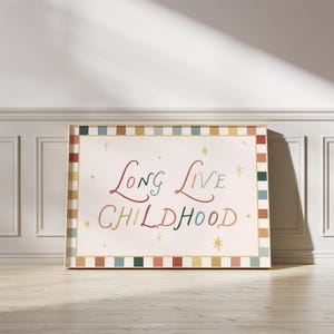 Pode incluir: Uma impressão de arte emoldurada com as palavras "Long Live Childhood" em escrita colorida. A obra de arte tem um fundo creme com uma borda decorativa de quadrados coloridos alternados. Estrelas douradas acentuam o texto.