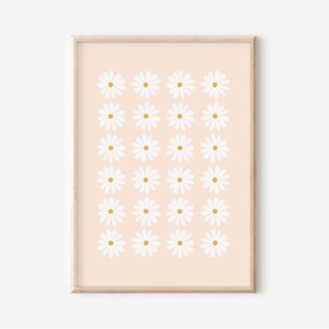 May include: A digital print of a pattern of white daisies with yellow centers on a peach background. The print is framed in a light wood frame.
