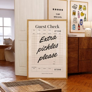 May include: A white and black guest check with the text "Guest Check" and "Extra pickles please" written in cursive. The check has a number "073940" printed on it.