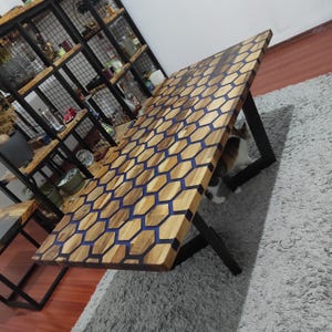 May include: A wooden table with a honeycomb pattern in blue epoxy resin. The table has black metal legs and is sitting on a grey rug.