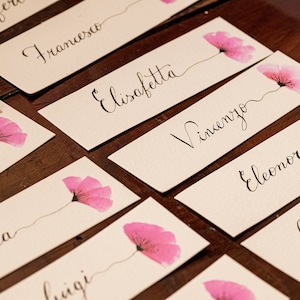 Naamkaartje voor bruiloft met roze bloemen, handgeschreven. Met de hand geschilderde en met de hand geschreven trouwkaart
