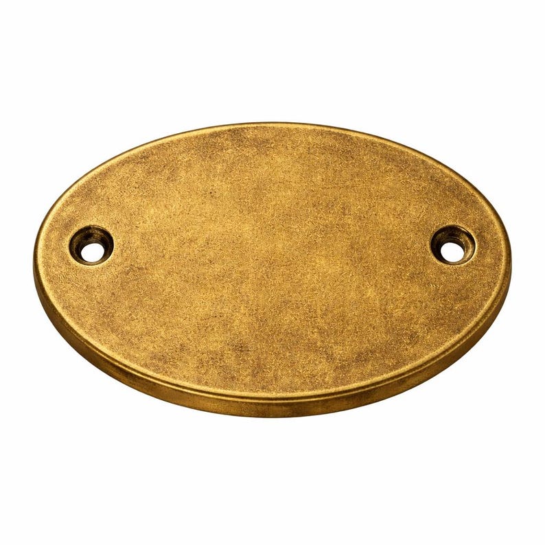 May include: An oval-shaped metal plaque with a distressed antique brass finish. The plaque features a smooth, flat centre surface and two circular mounting holes, one positioned on each side of the horizontal axis for secure attachment. custom brass plaque, custom brass sign, custom door sign, custom door plaque, custom entry sign, custom wall plaque, custom color plaque, color filled plaque, raised letter plaque, raised brass letters, raised letter sign, raised brass sign, dimensional plaque,
