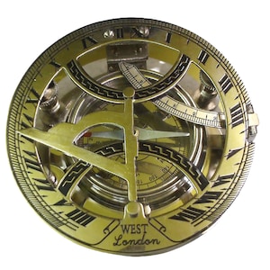 Könnte beinhalten: Ein antiker Sonnenuhrkompass aus Messing mit römischen Ziffern und einem drehbaren Gnomon. Der Kompass hat ein detailliertes Design mit einem kreisförmigen Zifferblatt und dem Text "WEST London". Der Kompass ist vor weißem Hintergrund.