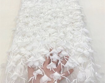 May include: White floral lace fabric with a delicate, 3D flower design. The lace is soft and sheer, with a subtle shimmer. It is perfect for creating elegant garments, accessories, and home decor.