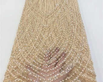 May include: Beige beaded lace fabric with a geometric pattern. The fabric is decorated with small pearls and sequins.
