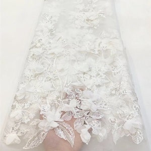 May include: White floral lace fabric with 3D flowers and sequins. The fabric is sheer and delicate.