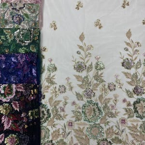 May include: A selection of embroidered fabrics in various colors, including pink, green, and navy blue. The fabrics feature floral and leaf designs with sequins and beads, and are displayed against a white background.