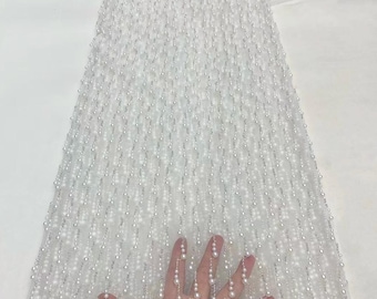 May include: White beaded fabric with a delicate mesh texture. The beads are arranged in vertical rows, creating a cascading effect. The fabric is soft and sheer, making it ideal for special occasions.