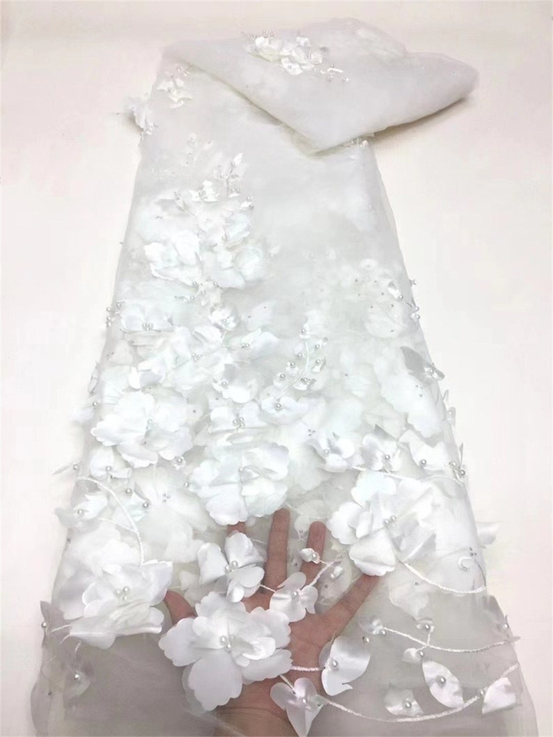 May include: White floral lace fabric with 3D flowers and pearl embellishments