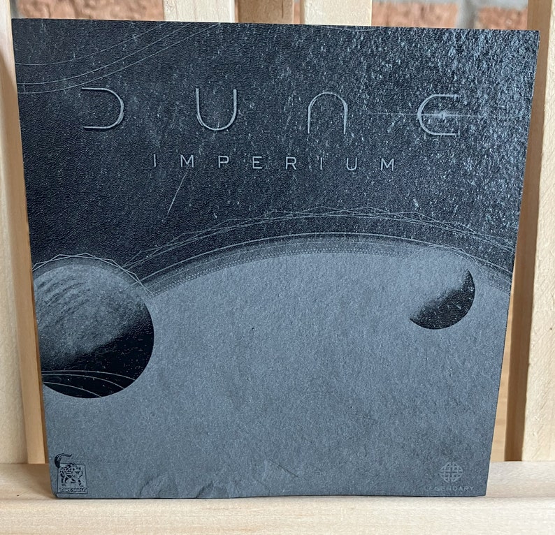 May include: A black and white image of a record album cover with the title "Dune Imperium" in white text. The album cover features a black and white image of a planet with rings.