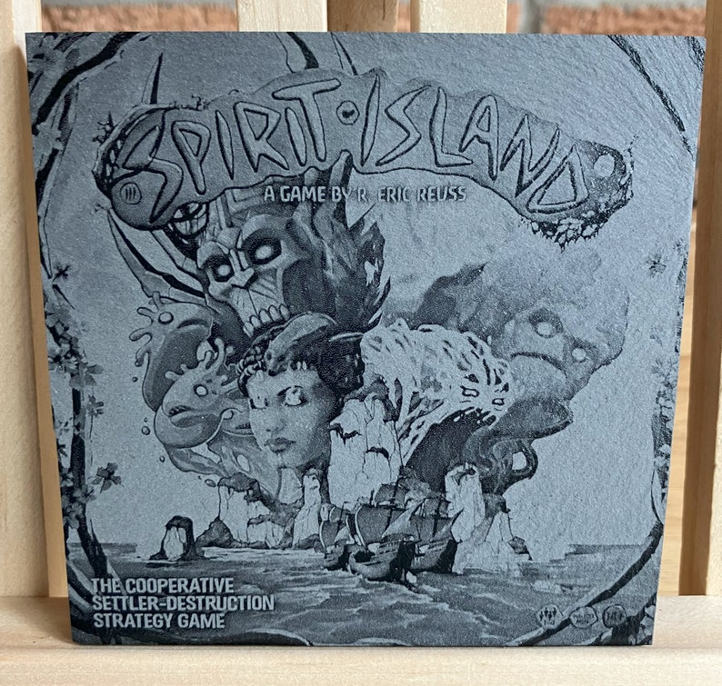 May include: A black and white image of a board game box cover for "Spirit Island: A Game by R. Eric Reuss". The cover features a stylised illustration of a mystical island with spirits and a ship sailing towards it. The text "The Cooperative Settler-Destruction Strategy Game" is printed below the title.