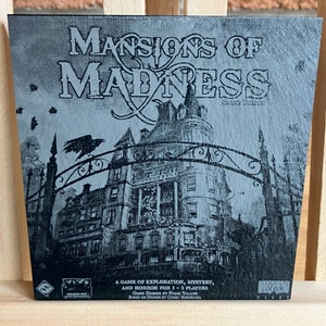 May include: A black and white image of a game box cover for "Mansions of Madness: Second Edition". The cover features a large, gothic mansion with a wrought iron gate and a raven perched on top. The text "Mansions of Madness" is written in a large, bold font.