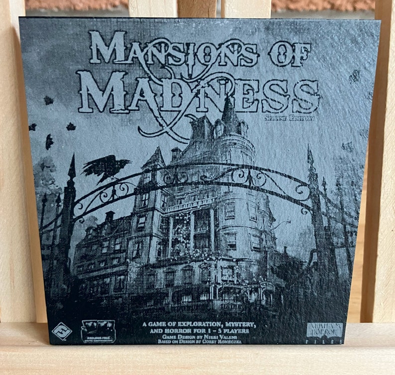 May include: A black and white image of a game box cover for "Mansions of Madness: Second Edition". The cover features a large, gothic mansion with a wrought iron gate and a raven perched on top. The text "Mansions of Madness" is written in a large, bold font.