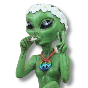 K&ouml;nnte beinhalten: Gr&uuml;ne Alien-Figur mit einem wei&szlig;en G&auml;nsebl&uuml;mchen-Stirnband, die in der einen Hand eine Zigarette und in der anderen ein Peace-Zeichen h&auml;lt. Das Alien tr&auml;gt eine Regenbogen-Friedenszeichen-Kette.