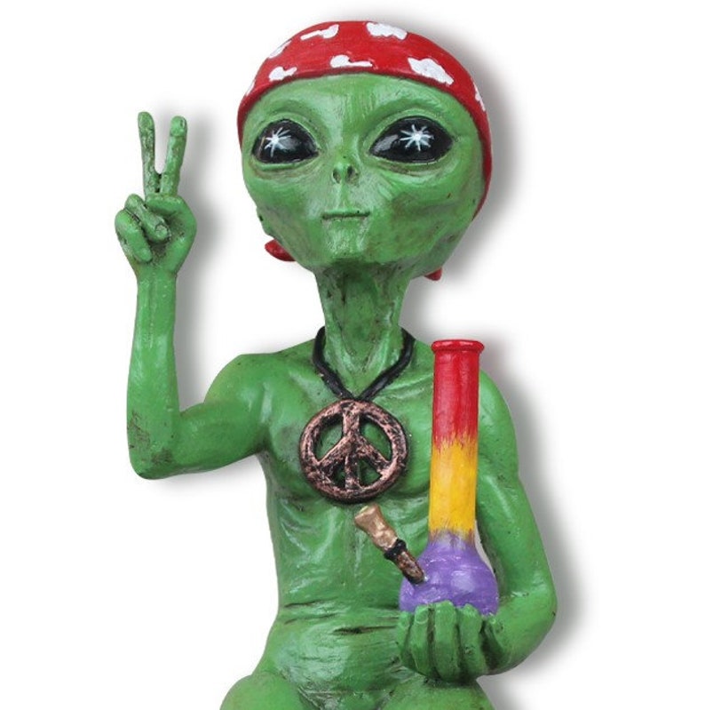 K&ouml;nnte beinhalten: Gr&uuml;ne Alien-Figur, die ein rot-wei&szlig;es Bandana mit einer Friedenszeichenkette tr&auml;gt und eine lila-gelbe Glasbong h&auml;lt.