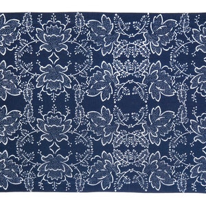 Op de afbeelding: Een donkerblauw tapijt met een wit bloemenpatroon. Het patroon bevat gestileerde bloemen en bladeren.