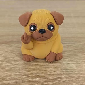 May include: A small, yellow pug figurine with brown ears and paws. The pug is giving the middle finger with its front paw. The figurine has large, round eyes and a grumpy expression. The background is a light wooden surface.