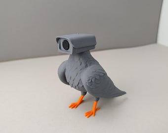 May include: A grey 3D printed pigeon figurine with orange feet, wearing a grey surveillance camera on its head.