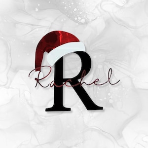 May include: A black letter "R" with a red and white Santa hat. The name "Rachel" is written in a cursive font over the letter. The background is a marbled pattern in shades of grey and white.
