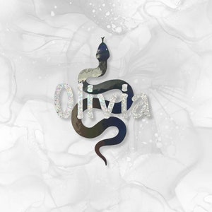 May include: A black snake silhouette with the name "Olivia" in silver glitter on a white background with grey and white marbling.