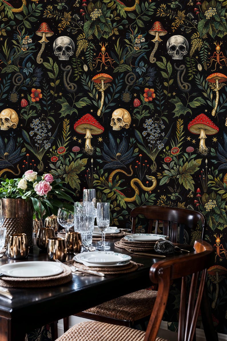 Op de afbeelding: Een donkere eetkamer met een zwarte behang met een herhalend patroon van schedels, paddenstoelen, slangen en bloemen. Een houten tafel is gedekt met witte borden, gouden onderborden en heldere glazen. Twee houten stoelen zijn zichtbaar.