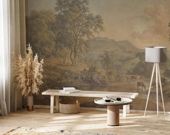 Puede incluir: Un banco de madera clara con una cesta tejida y una mesa de café redonda blanca con una base de madera. El banco y la mesa están frente a una pared con un mural de paisaje vintage que representa un río, árboles y colinas.