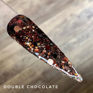 May include: A close-up of a nail polish color called "Double Chocolate". The polish is a dark brown base with a mix of gold, copper, and red glitter.