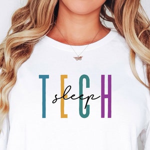 Könnte beinhalten: Weißes T-Shirt mit dem Text "TECH sleep" in bunten Buchstaben. Die Buchstaben sind türkis, gelb, türkis und lila.