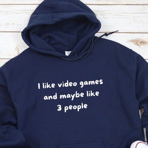 May include: A navy blue hoodie with a white graphic that says "I like video games and maybe like 3 people".
