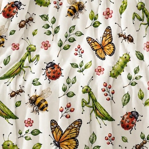Op de afbeelding: Een witte plaid met een herhalend patroon van insecten en botanische elementen. Het ontwerp bevat oranje monarchvlinders, groene bidsprinkhanen, rode lieveheersbeestjes, geel-zwarte bijen, groene rupsen en mieren.